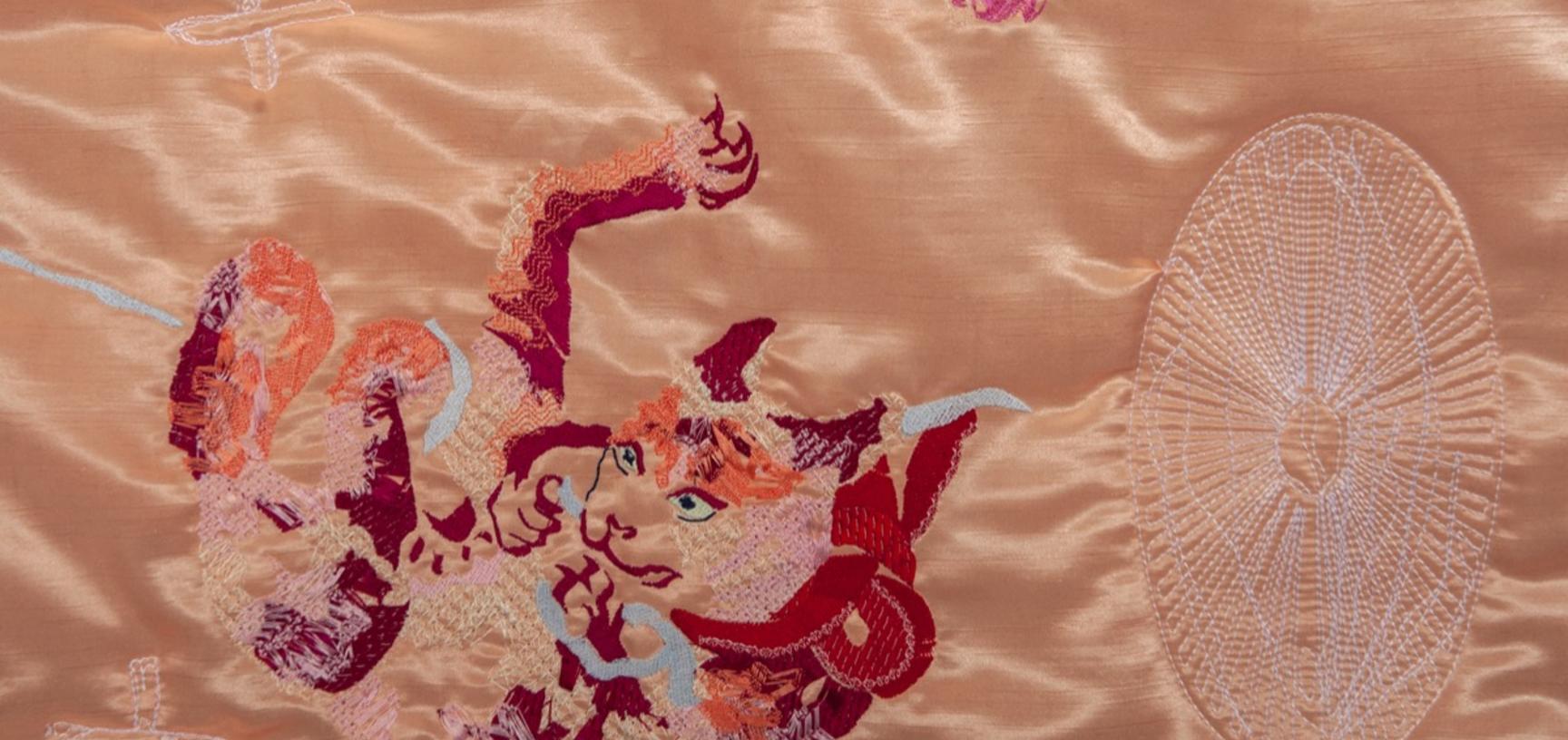 Close-up of a machine-embroidered cat on a satin quilt.