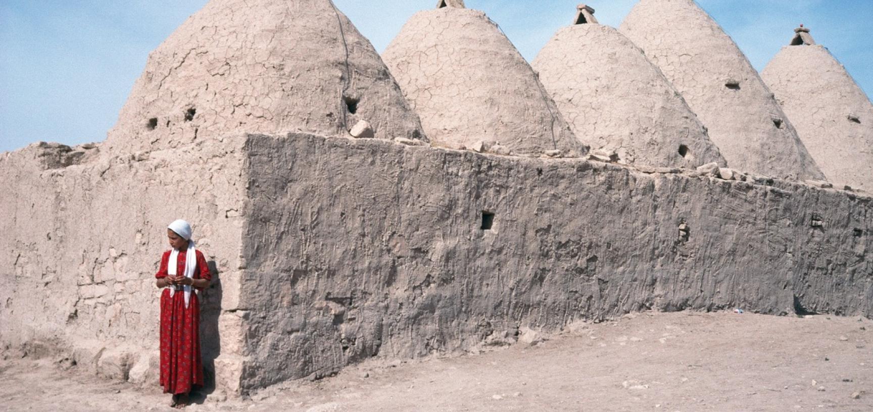 Woman outside interlinked domed houses in Anatolia