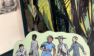 Close up view of a display case showing an illustration of five figures on a stand in front of illustrated foliage and an nineteenth-century photograph a person.